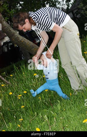 Un anno di età del bambino ad imparare a camminare da azienda di sua madre le mani Foto Stock