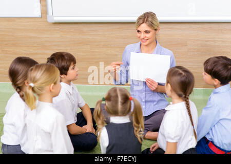 Insegnante e i bambini sono seduti in cerchio insieme. Foto Stock