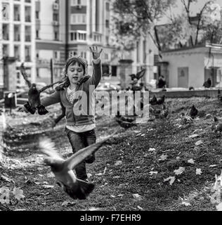 22/09 - Giovane ragazza insegue piccioni in un parco locale a Ufa Russia durante l'autunno 2015 Settembre Foto Stock