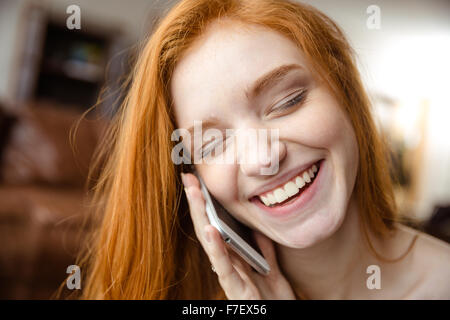 Closeup ritratto di un sorridente redhead donna con gli occhi chiusi a parlare al telefono Foto Stock