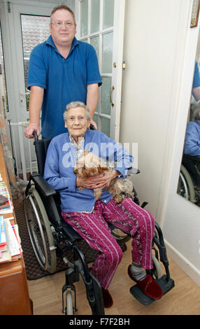 Caregiver maschio spingendo una donna anziana in una sedia a rotelle (potrebbe essere madre e figlio) Foto Stock