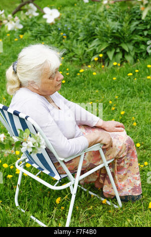 La nonna in giardino sotto una fioritura del melo Foto Stock