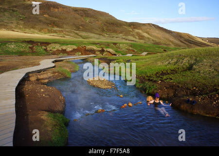 La gente seduta in hot spring creek, Hengill montagne, Hveragerdi, SW Islanda Foto Stock