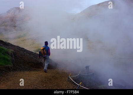 Escursionista passando primavera calda e fumante, Hengill montagne, Hveragerdi, SW Islanda Foto Stock