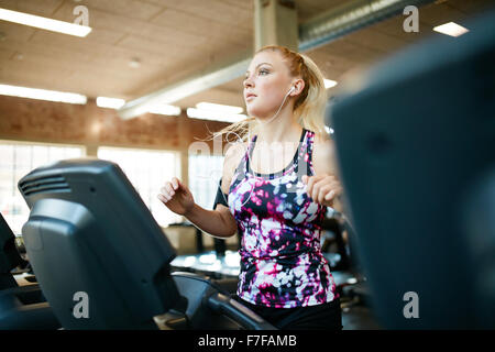 Scatto di una donna in corsa sul tapis roulant in palestra. Giovane femmina focalizzato lavorando presso un club salute, formazione su attrezzatura ginnica Foto Stock