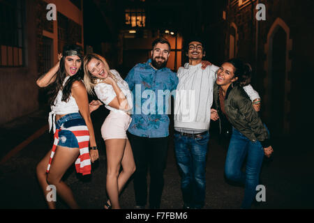 Ritratto di giovani uomini e donne che cercano in telecamera a ridere. Multirazziale del gruppo di giovani amici appendere fuori all'aperto in parte. Foto Stock