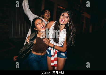 Ritratto di tre giovani amici avente parte all'aperto. Allegro giovani migliori amici appendere fuori a notte. Foto Stock