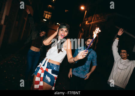 Ritratto di Allegro giovani in festa con fuochi d'artificio all'aperto durante la notte, giovani amici partying con botti su 4 Foto Stock