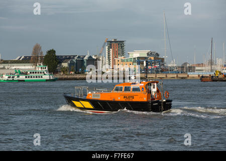 Arancione e nero barca pilota attraversando il porto di Portsmouth in velocità. Gosport traghetto può essere visto in background. Foto Stock