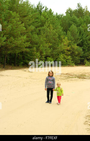 Piccoli viaggiatori sorelle andare sulla strada forestale tenendo le mani Foto Stock