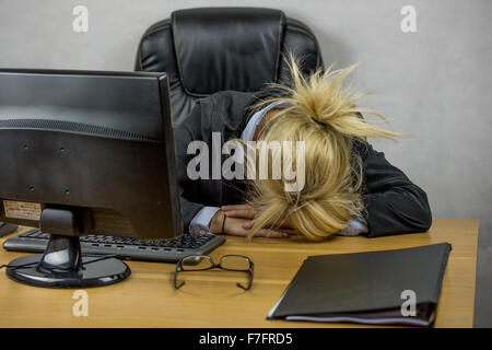 Una femmina di lavoratore di ufficio seduto alla sua scrivania su di lei da 9 a 5 job Foto Stock