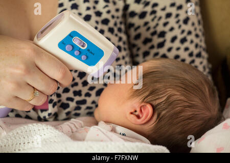 Mamma controllo neonato la temperatura con un termometro a infrarossi Foto  stock - Alamy