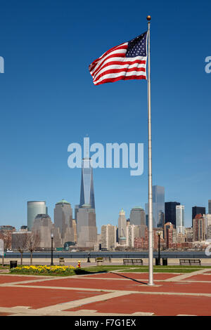 Bandiera americana indipendente alto in Liberty State Park, New Jersey, con una vista della parte inferiore di Manhattan grattacieli di New York City Foto Stock