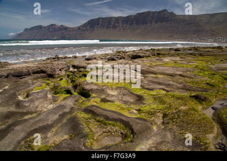 Spiaggia di Famara, Playa de Famara, costa ovest di Lanzarote, con El Risco scogliere al di là. Foto Stock