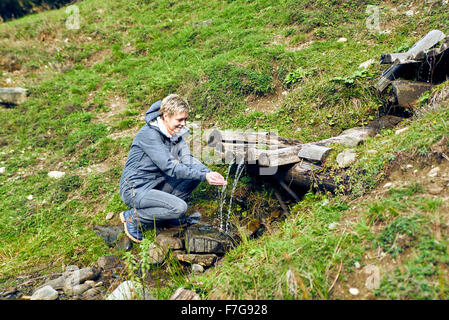 Ragazza beve acqua pulita da una primavera in montagna Foto Stock