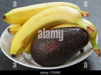 Le banane in una ciotola con un avocado per accelerare il processo di maturazione - impostazione domestica , REGNO UNITO Foto Stock