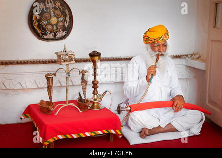 Indian man in turban fumare narghilè, Forte Mehrangarh, Jodhpur, Rajasthan, India Foto Stock
