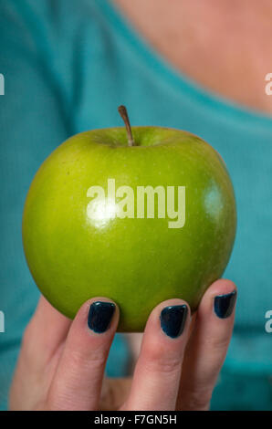 Donna che mantiene una mela verde nel suo dito suggerimenti Foto Stock