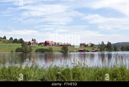 JAMTLAND, SVEZIA IL 07 AGOSTO 2015. Vista di terreni coltivati, lago e un villaggio rurale. Rosso di edifici di legno sul lato opposto. Editoriale. Foto Stock