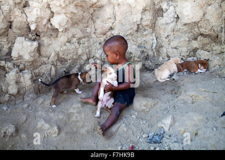 COX's Bazar, BANGLADESH - 29 novembre: Achild giocando con il cane i bambini a Kutubdia isola il 29 novembre 2015. Kutubdia, un isola a Cox's Bazar costa. le avversità di natura principalmente indotta dal cambiamento climatico. Durante gli ultimi due decenni gli impatti del clima in Bangladesh sono stati accellerating.Kutubdia è anche colpito duramente. Il posto è molto vulnerabile ai cicloni e mareggiate, che sono diventati più frequenti e intense in Bangladesh nonché innalzamento del livello del mare e le onde più forte. Il risultato è la massiccia erosione e salininty intrusione, non solo la distruzione di terre agricole, ma causin Foto Stock