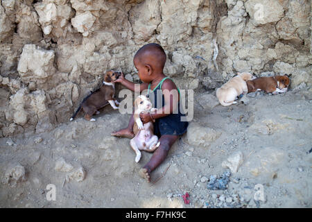 COX's Bazar, BANGLADESH - 29 novembre: Achild giocando con il cane i bambini a Kutubdia isola il 29 novembre 2015. Kutubdia, un isola a Cox's Bazar costa. le avversità di natura principalmente indotta dal cambiamento climatico. Durante gli ultimi due decenni gli impatti del clima in Bangladesh sono stati accellerating.Kutubdia è anche colpito duramente. Il posto è molto vulnerabile ai cicloni e mareggiate, che sono diventati più frequenti e intense in Bangladesh nonché innalzamento del livello del mare e le onde più forte. Il risultato è la massiccia erosione e salininty intrusione, non solo la distruzione di terre agricole, ma causin Foto Stock