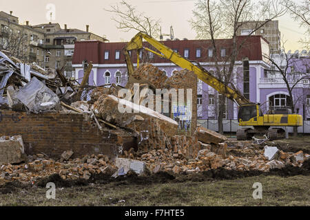 Escavatore e rovine del vecchio edificio in mattoni Foto Stock