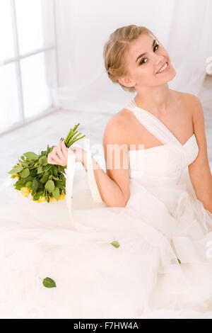 Ritratto di un sorridente sposa azienda fiori matrimonio e guardando la fotocamera Foto Stock