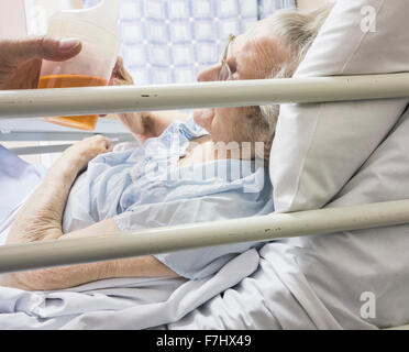 Figlio di incoraggiare novantenne madre a bere il fluido nella nazione Servizio Sanitario ospedale in Inghilterra, Regno Unito. Foto Stock