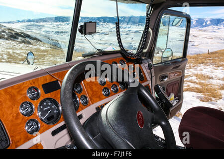 Il Wyoming, STATI UNITI D'AMERICA vista dalla cabina di Peterbilt 379 carrello parcheggiato in un tirare fuori vista panoramica con cruscotto e colline innevate sullo sfondo Foto Stock