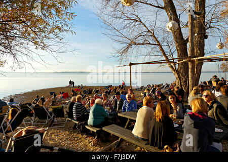 Le persone in un momento di relax a un giardino della birra sulla spiaggia, foreshore Feldwieser Bay, Chiemsee, Alta Baviera, Germania, Europa. Foto Stock