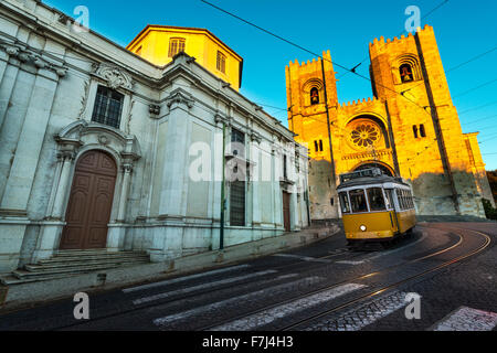 Il tram di fronte alla Cattedrale di Lisbona al tramonto Foto Stock