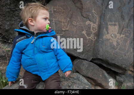 Il Toddler boy studiando petroglyph nel Parco Nazionale di Yellowstone, STATI UNITI D'AMERICA Foto Stock
