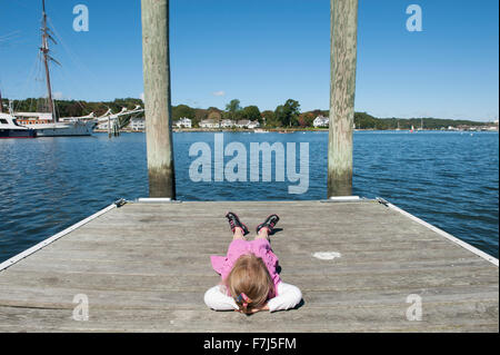 Bambina giacente sul dock con le mani dietro la testa Foto Stock