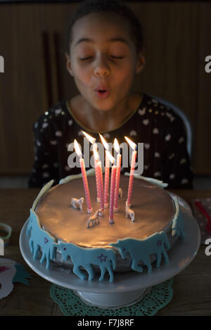 Ragazza soffiando le candeline sulla torta di compleanno Foto Stock