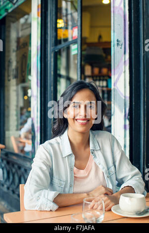 Donna seduta al cafè sul marciapiede Foto Stock