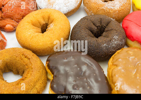 Chiudere la vista di un gruppo assortiti di ciambelle glassate e barre di ciambella nel fondo di una scatola di cartone. Foto Stock