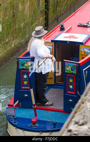 Donna che guida nave stretta narrowboat sul canale Kennet e Avon, Devizes, Wiltshire, Inghilterra, Regno Unito nel mese di agosto Foto Stock