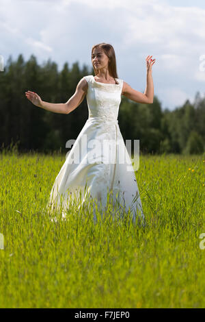 Giovane ragazza in un abito da sposa in ballo nel campo. Foto Stock