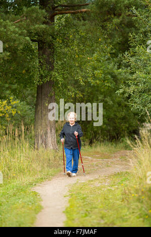 Donna anziana è impegnato nel Nordic walking nel parco. Foto Stock