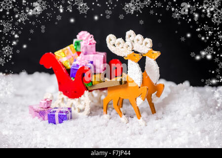 Bella composizione della decorazione di natale renne e Santa sleigh con doni in neve su sfondo nero, primo piano Foto Stock