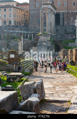 Roma, Italia. I visitatori nel Foro Romano a piedi verso le rovine del Tempio di Saturno. Foto Stock