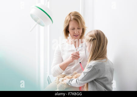 Pediatra con ragazza paziente e orsacchiotto nella sala esame Foto Stock