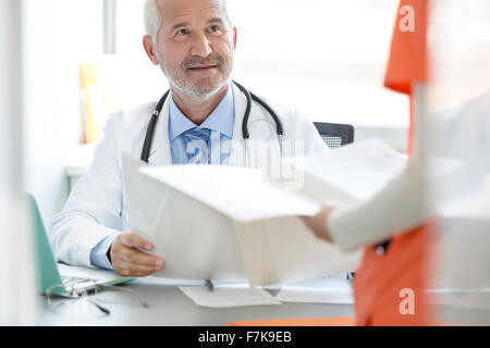 Medico e infermiere rivedendo medical record nell'ufficio del medico Foto Stock