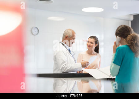 Il medico e il paziente discutendo medical record alla stazione di infermieri Foto Stock