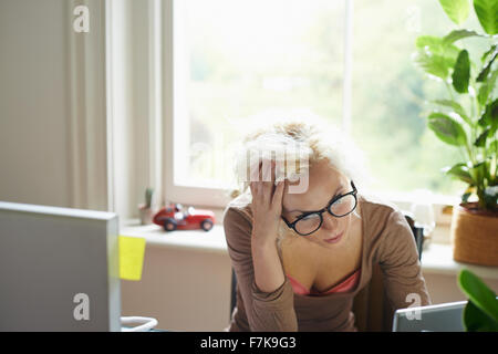 Ha sottolineato la donna con le mani nei capelli lavoro in ufficio Foto Stock