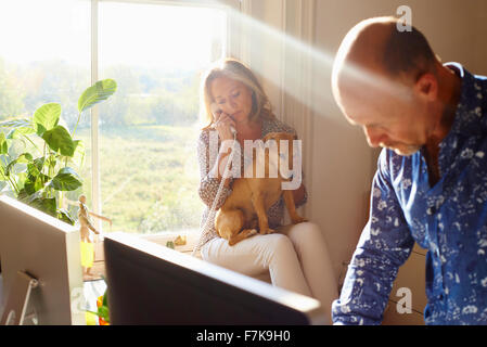 Giovane con cane in sunny home office Foto Stock