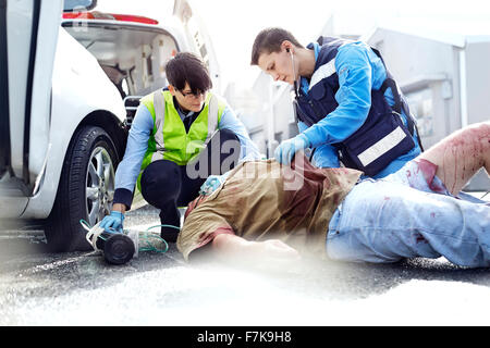 Gli operatori di soccorso che tende ad auto vittima di incidenti in strada Foto Stock