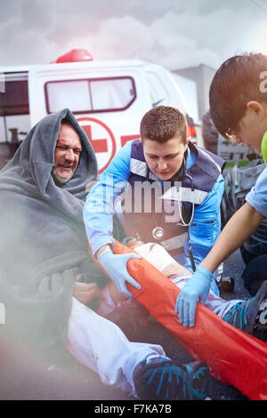 Gli operatori di soccorso preparazione vuoto fissatore gamba sulla vettura vittima di incidenti in strada Foto Stock