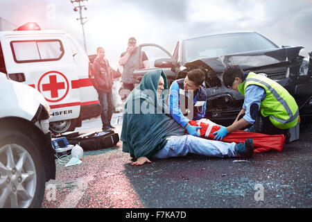 Gli operatori di soccorso preparazione vuoto fissatore gamba sulla vettura vittima di incidenti in strada Foto Stock
