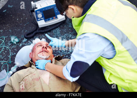 Lavoratore di salvataggio tendente ad auto vittima di incidenti in strada Foto Stock